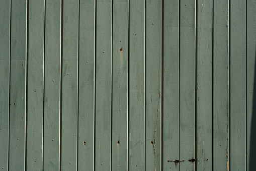 Section of a plain dirty green wooden fence.