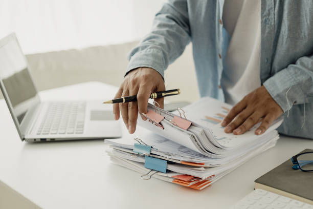 istock Successful accounting businessman in suit with paperwork, documents, reports in hand working inside office Satisfied with achievement, celebrating victory using laptop. Close-up pictures. 2137741956
