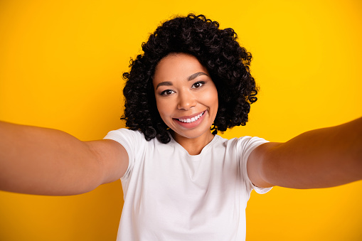 Photo of sweet cheerful lady dressed white t-shirt smiling recording video vlog isolated yellow color background.