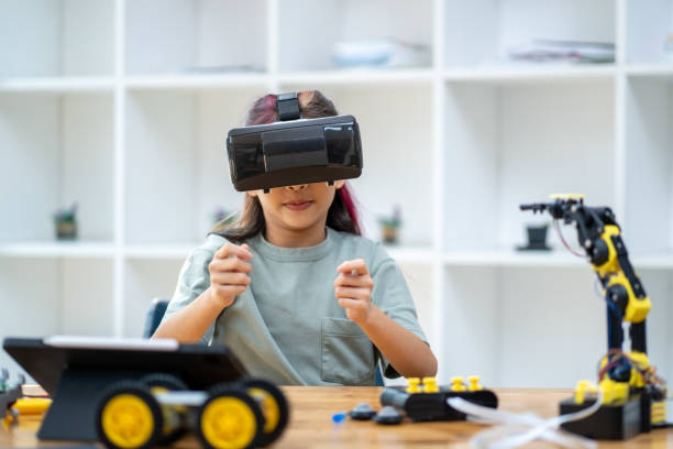 istock Young girl wearing a VR headset sits on a table moving her hands around. to work on assembling virtual robots ,technology concept 2137781805