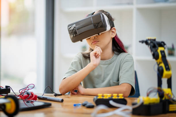 istock Young girl wearing a VR headset sits on a table moving her hands around. to work on assembling virtual robots ,technology concept 2137782317