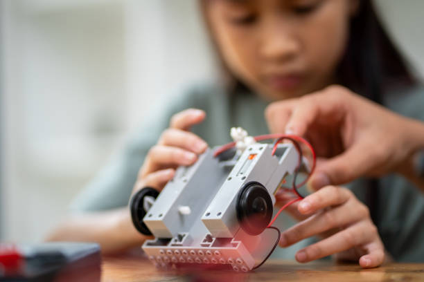istock Close-up of smart girl using small tools to assemble robot by learning from tablet computer, technology concept 2137783375