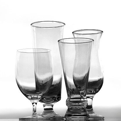 The photograph showcases four elegant cups arranged against a white background, enhancing their beauty and detail. Each cup is meticulously outlined, creating a sharp contrast that highlights its shape and structure. The symmetrical arrangement of the cups adds visual balance to the composition, while the soft lighting enhances the reflections and shadows, providing depth and dimension to the image. This capture conveys a sense of refinement and elegance, inviting the viewer to appreciate the delicacy and artistry in every detail of the cups.