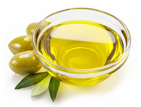 Glass bowl of olive oil and olive berries isolated on white background.