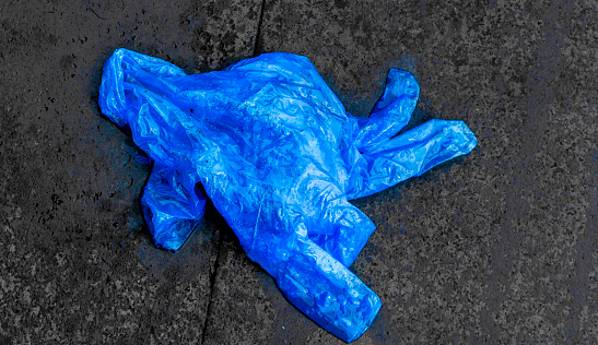 A blue plastic glove rests on a sidewalk