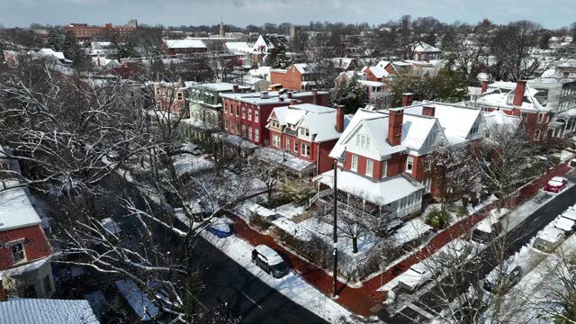 American city suburb housing sunny winter day with snow. Aerial tilt down revealing historic homes in town.
