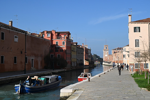 Venice, Italy, march 12, 2024 : Quay and canal leading towards the Venice Arsenal with a delivery boat in the foreground and the Paradise Bridge in the background