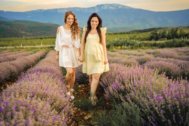 Two female friends walking through lavender field at sunset
