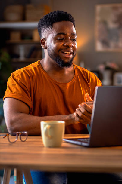 istock Smiling young African American man sitting at home using laptop for video call. 2137867035