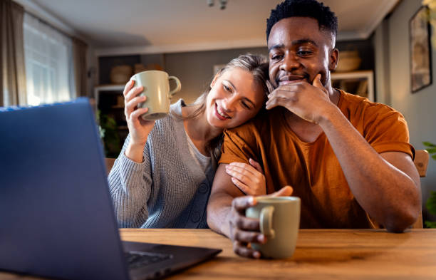 istock Smiling young mixed couple using a laptop while working on their home finances. 2137867058