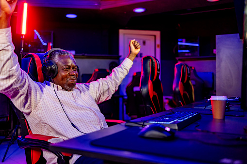 Senior man celebrates victory in video game with a clenched fist and a smile