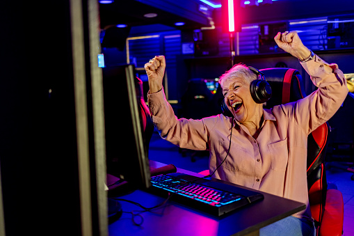 Cute senior woman feeling happy and excited for winning computer video game.