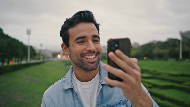 istock Positive tourist video calling by mobile phone spending weekend in park close up 2137912471