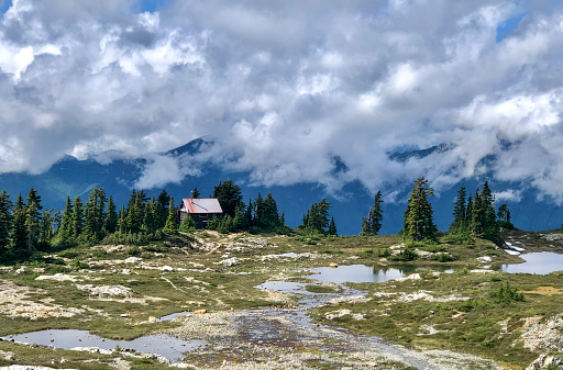 Mountain hut in alpine meadow, lofty clouds above