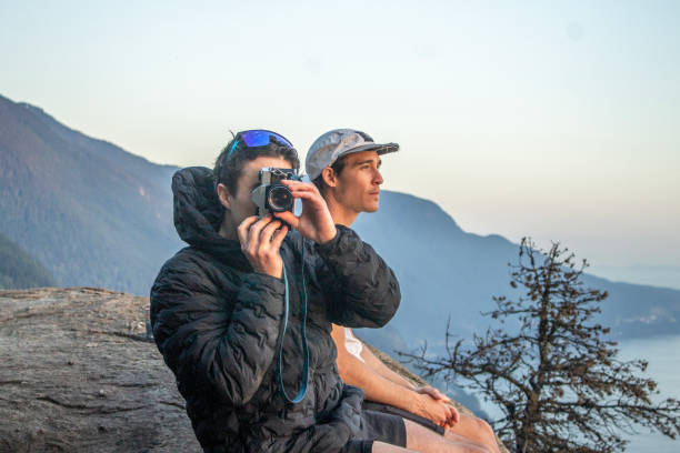 Hikers take photo on top of mountain above ocean
