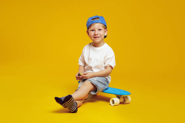 istock Handsome boy wearing trendy blue cap and white t-shirt, smiling while sitting on modern skateboard. 2137925126