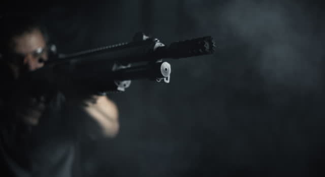Slow-Motion High-Speed Shot of Man Aiming and Firing Shotgun, Close-Up of Powerful Blast with Smoke