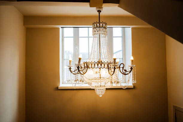 An amber chandelier fixture hangs in front of a rectangle window. The hardwood ceiling contrasts beautifully with the shades of the tinted glass