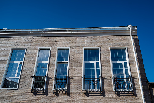 A row of rectangular sash windows adorns the brick facade of a city building, contrasting beautifully against the electric blue sky in the background