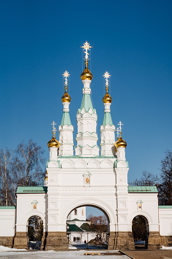 A white building with a facade featuring three gold crosses on top, set against the sky. This architectural fixture is a place of worship and symbolizes holy places