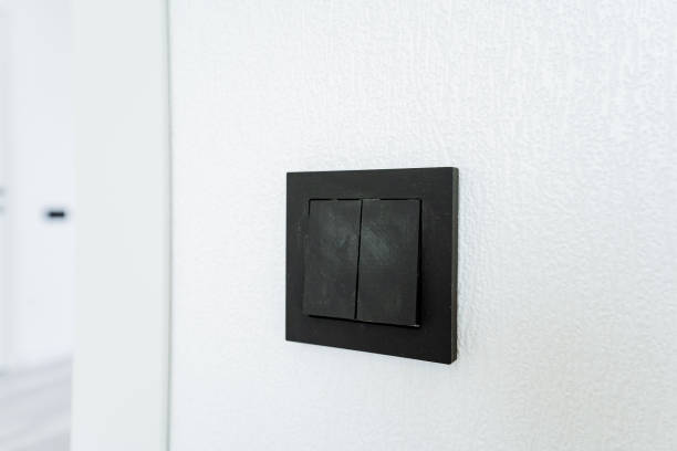 istock A black light switch is mounted on a white wall in a room with a television set 2137945644
