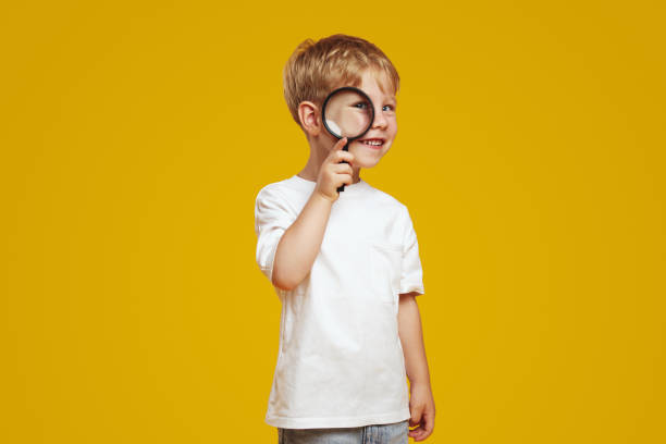 istock Exited curious little kid in white tshirt looking at camera through magnifier whit toothy smile. 2137951962