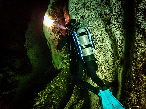 A local female scuba diver shines a dive light into the spring vent underwater at Blue Springs State Park, Volusia County, Florida