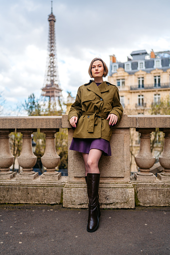 Portrait of a beautiful young woman standing on the street in front of an Eiffel Tower in Paris in France.