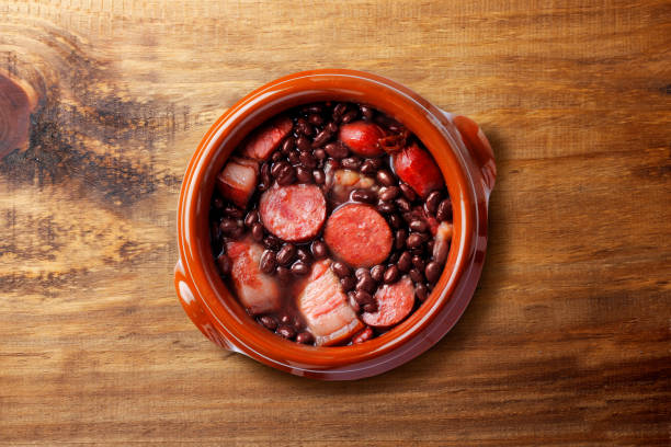 Brazilian feijoada, traditional food from Brazil cuisine, on ceramic casserole bowl, over rustic wooden table