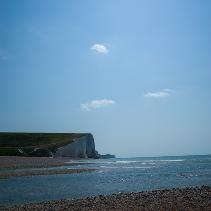 The beginning section of the Brighton Seven Sister White Cliff taken from the right side under bright blue sky. The lower part of the picture is the sea and pebble beach.