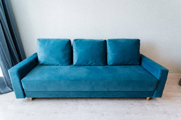istock Electric blue studio couch with pillows in a living room next to a window 2138024995
