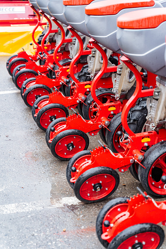 A line of tractors with vibrant red wheels are neatly parked in the lot, showcasing the automotive wheel system