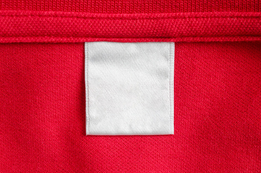 Blank white laundry care clothes label on red shirt fabric texture background