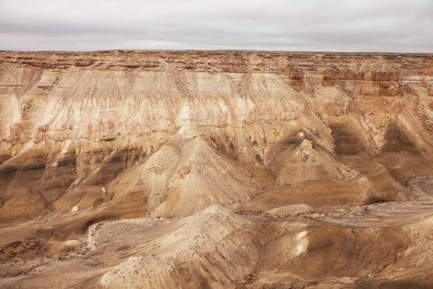 istock Layered sedimentary rock formations in a dry desert canyon under a cloudy sky 2138064018