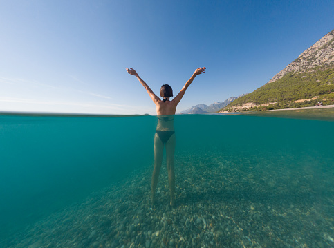 Woman on tropical vacation paradise on sea. Summer sea joy in Turkish seacoast, beaches along Lycian Way, Turkish Riviera. Asian female underwater and turquoise ocean around.