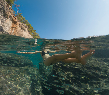 Young female on holidays enjoy floating on a crystal clear water beach of Antalya Turkey. Asian beautiful woman swimming with open arms. Relax and tranquility. Travel and Holiday concept.