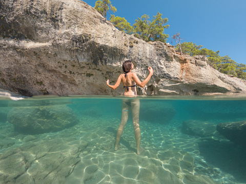 Woman on tropical vacation paradise on sea. Summer sea joy in Turkish seacoast, beaches along Lycian Way, Turkish Riviera. Asian female underwater and turquoise ocean around.
