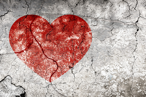 Broken heart concept with bleeding heart on cracked wall