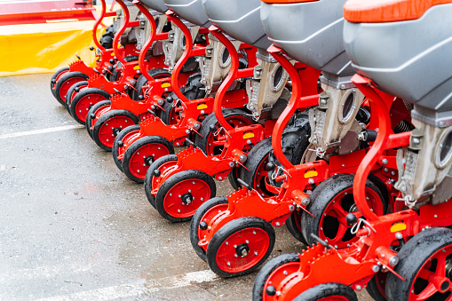 A row of red and black tractors with automotive tires and synthetic rubber treads are lined up in a parking lot, showcasing automotive design and innovative plant engineering