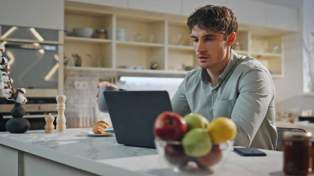 istock Handsome freelancer working laptop sitting kitchen close up. Man drinking coffee 2138142991