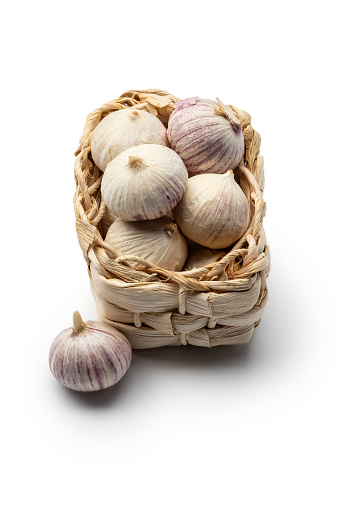Asian garlic in a reed basket, isolated on a white background. High angle view, studio shot.