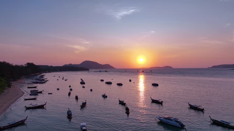 Morning sunrise on the beach with many fishing boats and tourist boats floating