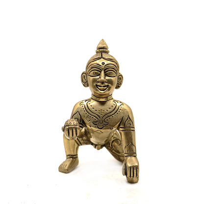 vintage golden figure of crawling baby lord krishna also called gopal with sweet laddu in his hand isolated in a white background