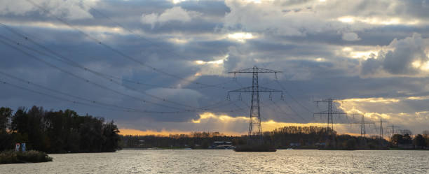 istock high voltage electric tower with cloudy sky background beside lake, pylon, sunset 2138176252