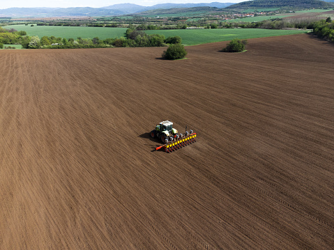 Tractor sows fields. Drone stock photo of a tractor with a seeder that is sowing fields