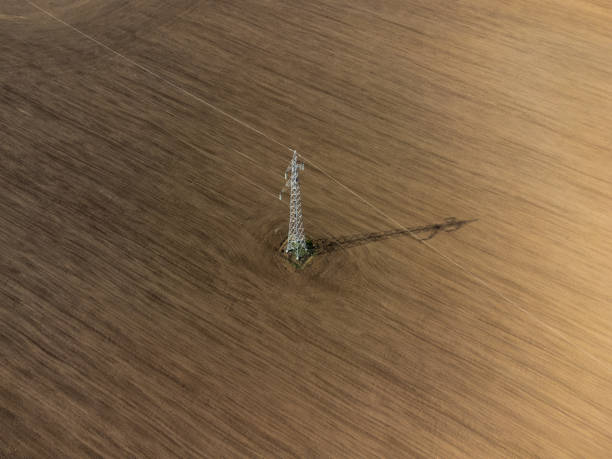 Drone stock photo of a transmission pole in the middle of an agricultural field