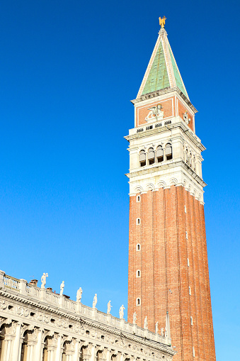 St Marks Campanile (Bell Tower) towering above from St Marks Square against blue sky, one of the notable tourist attractions in Venice, Italy