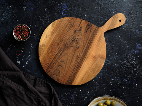 Top view of a beautiful round wooden board, decorative fabric towel, olives and spices. Blank template for designing a cafe or restaurant menu.