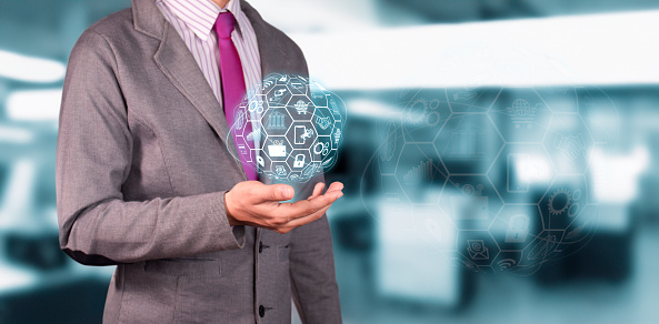 businessman holds globe hologram with business and company icons.