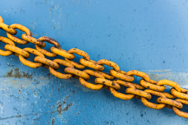 rusted yellow chain hanging across a ships weathered blue hull contrasting abstract pattern